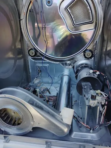 Dryer blower wheel and drive motor exposed during a dryer repair