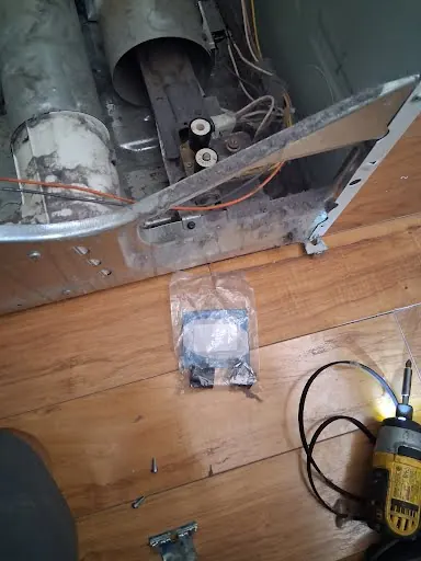 Technician testing dryer exhaust duct airflow with the dryer pulled out
