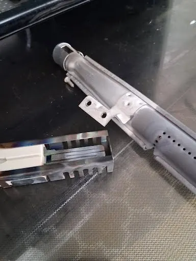 Gas oven bake burner removed from the oven cavity for inspection