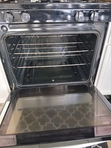 Gas range with the oven door open after an oven heating repair