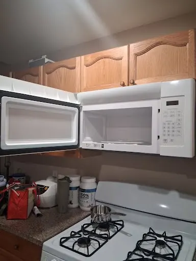 Over-the-range microwave open above a gas range during a microwave repair