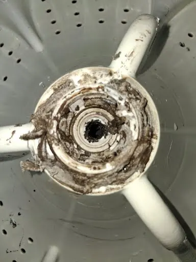 Washer with agitator removed showing detergent and hard-water residue
