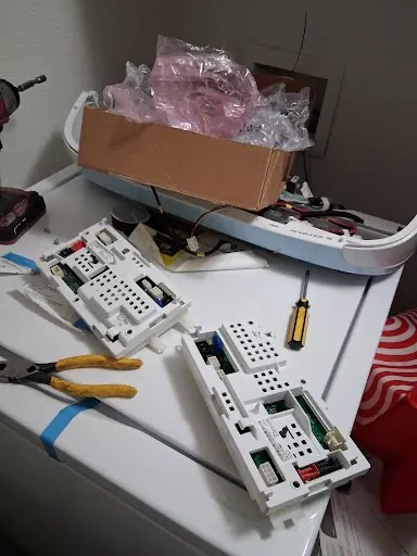 Old and new washer control boards side by side during a board replacement
