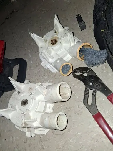Washer drain pumps on the floor during a drain pump replacement